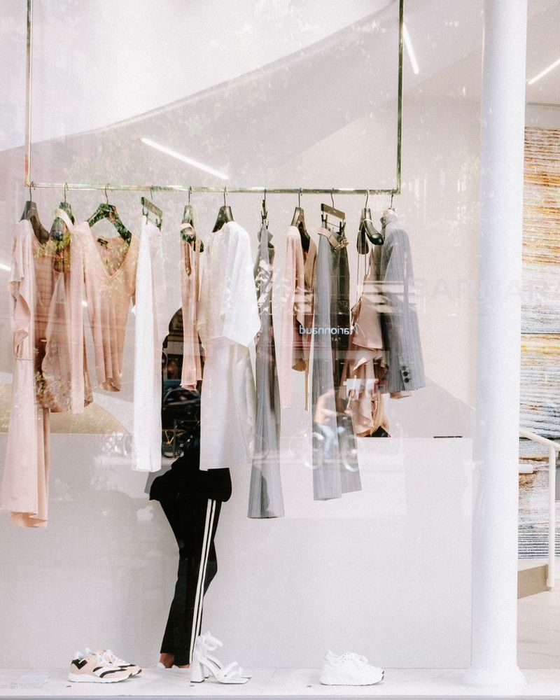 Une cliente choisit une pièce sur un portant, dans une boutique claire